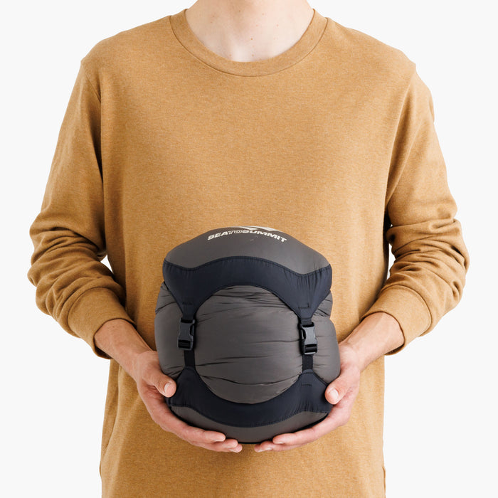 Person som håller en packad Ascent dunsovsäck